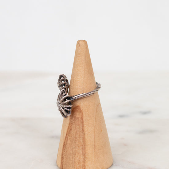 Silver ring on a wooden cone against a marble background