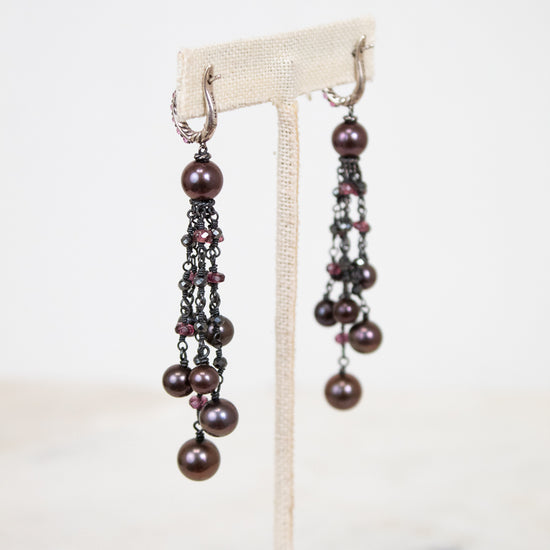 Pair of pearl earrings on a white stand with a light background