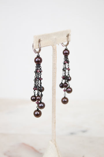 Pair of pearl earrings on a white stand with a light background