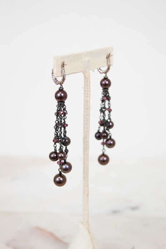 Pair of pearl earrings on a white stand with a light background