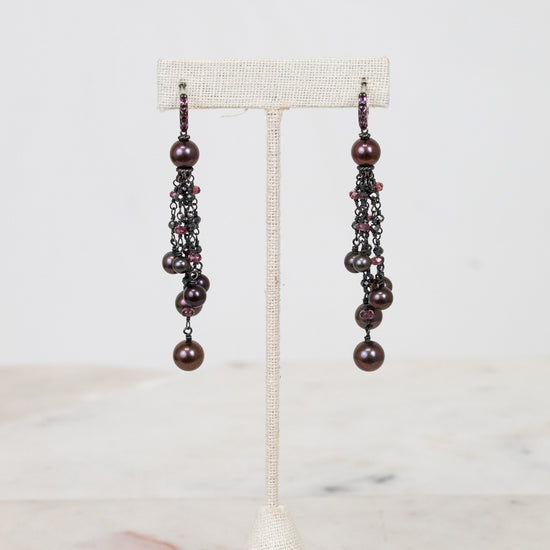 Pair of pearl beaded earrings on a white stand with a light background