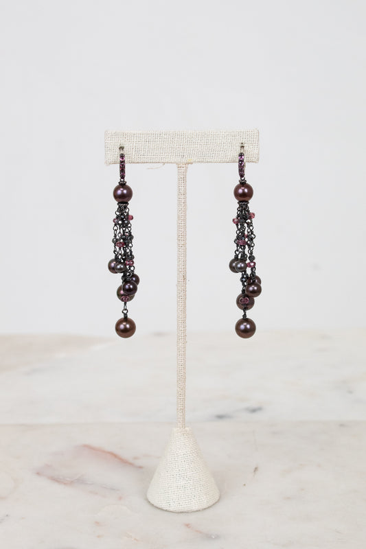 Pair of pearl beaded earrings on a white stand with a light background