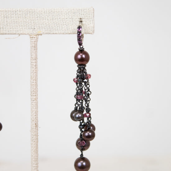 Pair of dangling earrings with pearls and beads on a white background