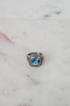 Silver ring with a blue gemstone on a marble surface