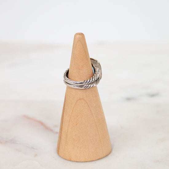 Silver ring on a wooden cone against a marble background