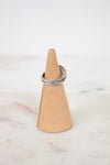 Silver ring on a wooden cone against a marble background