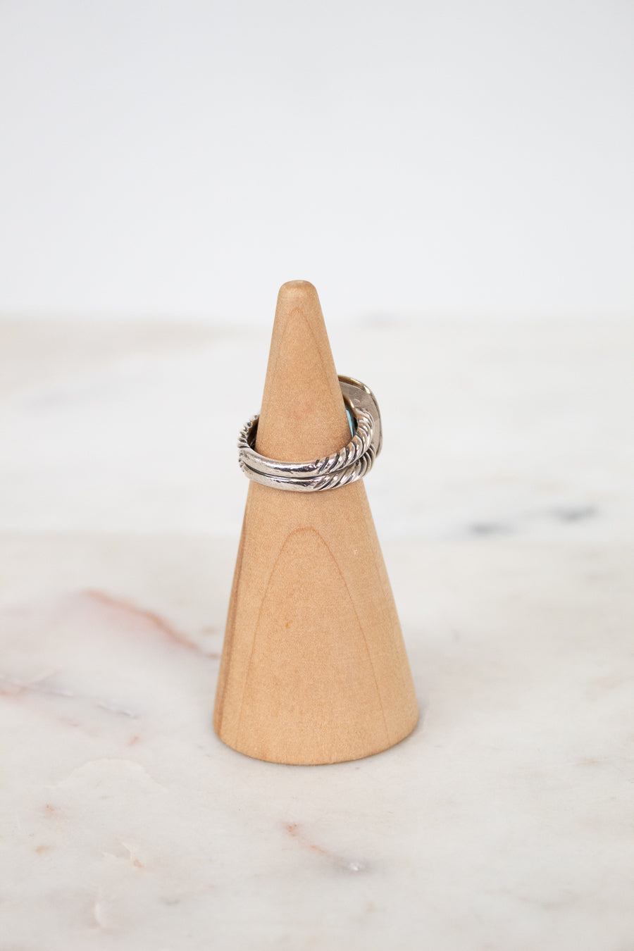 Silver ring on a wooden cone against a marble background
