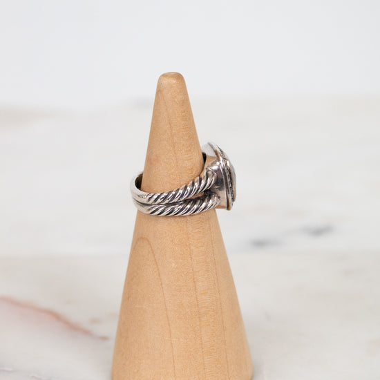 Silver ring on a wooden cone against a marble background