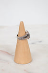 Silver ring on a wooden cone against a marble background