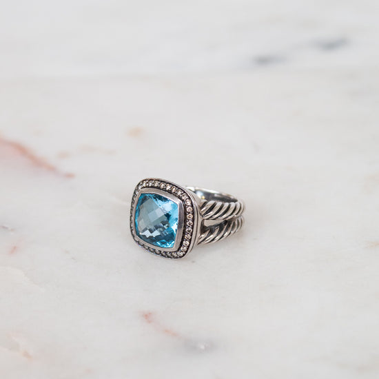 Silver ring with a blue gemstone on a marble surface