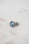 Silver ring with a blue gemstone on a marble surface