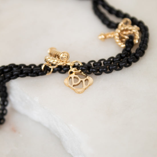 Black chain with gold charms on a white surface