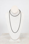 Black necklace on a white mannequin bust against a light gray background