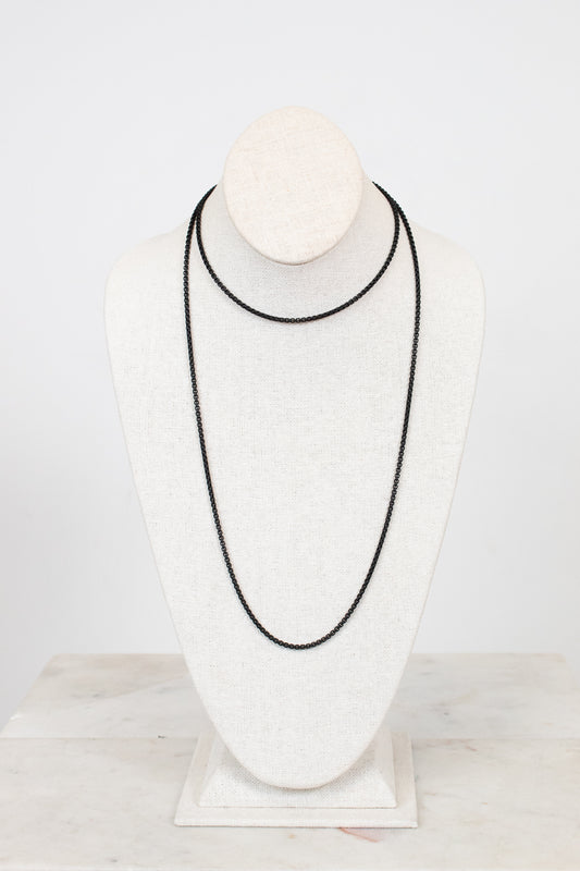 Black necklace on a white mannequin bust against a light gray background