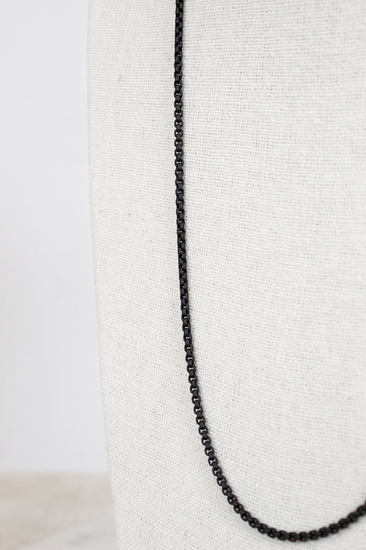 Black chain necklace on a white fabric background