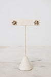 Silver and gold layered overlap 'X' stud earrings displayed on plain post against a marble and white background
