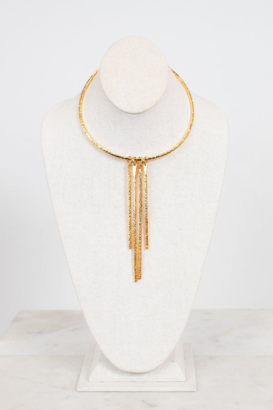 A gold-toned choker necklace with three dangling chain fringe elements, displayed on a white fabric jewelry bust against a clean white background.