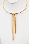 A gold-toned textured necklace displayed on a white fabric mannequin bust. The necklace features a circular top band with five dangling vertical bars hanging from a central connector.