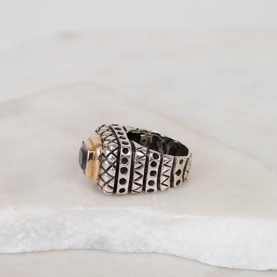 Silver ring with gold accents on a textured white surface