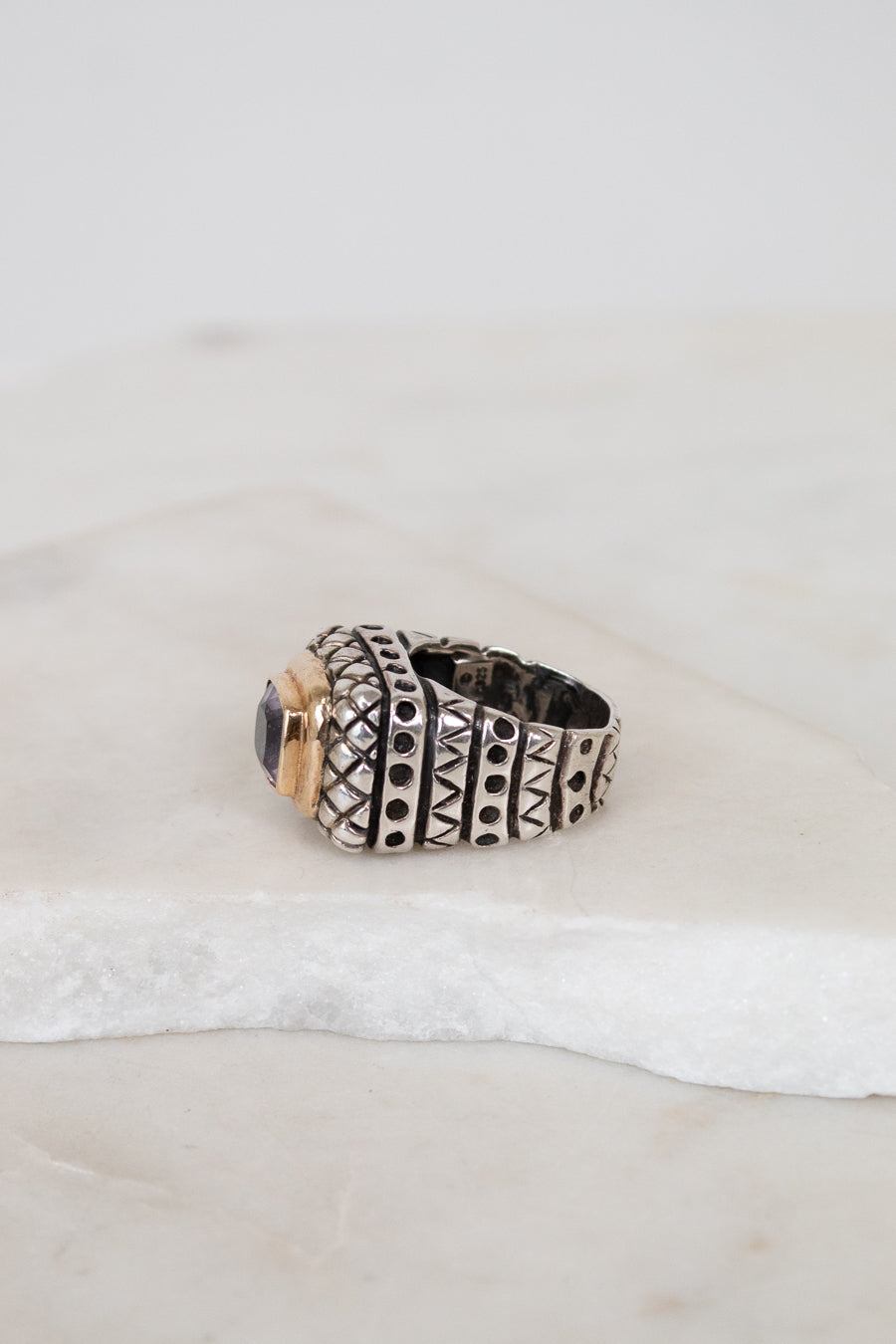 Silver ring with gold accents on a textured white surface
