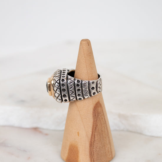 Silver ring on a wooden stand with a white background