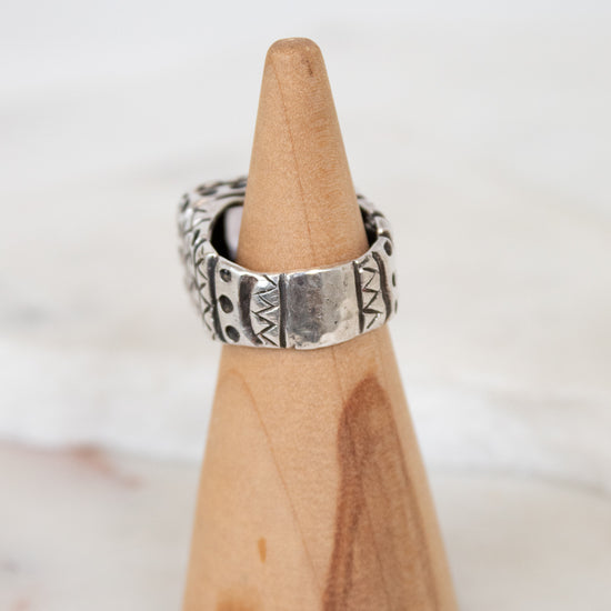 Silver ring on a wooden cone against a white background