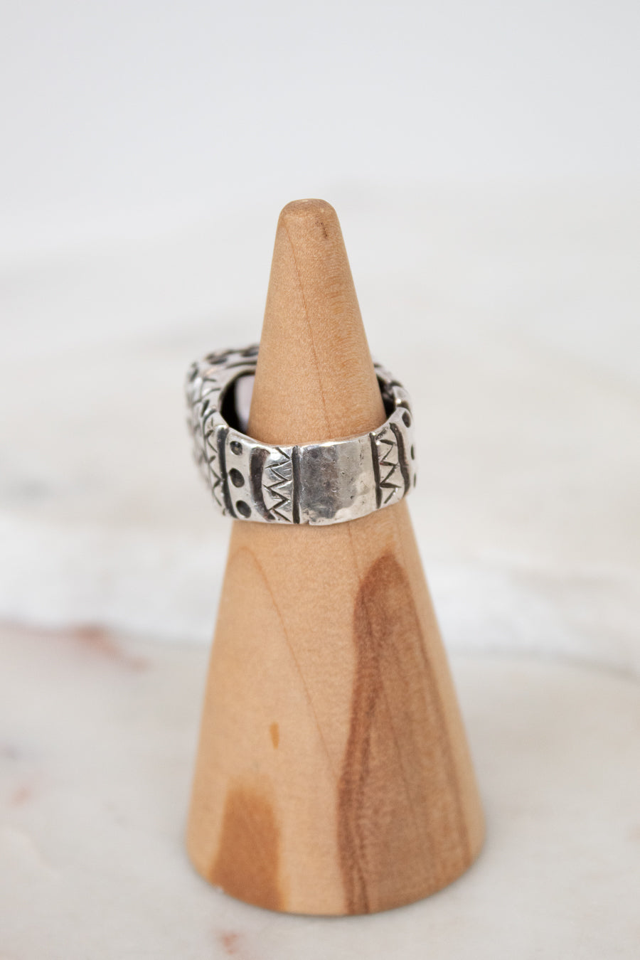 Silver ring on a wooden cone against a white background