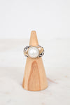 Ring with a pearl on a wooden stand against a white background