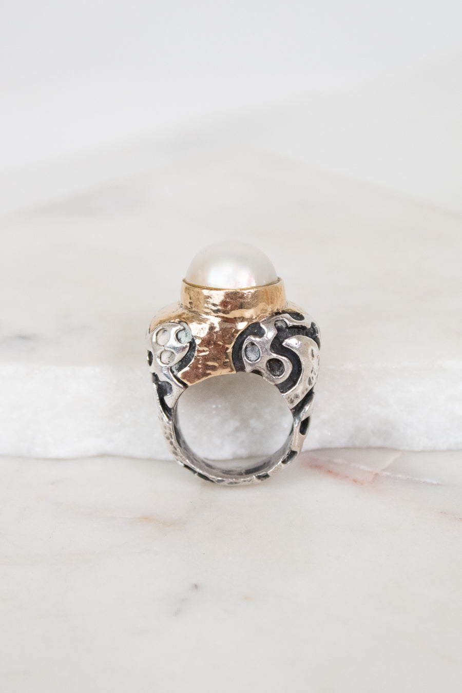 Ring with pearl detail on a marble surface