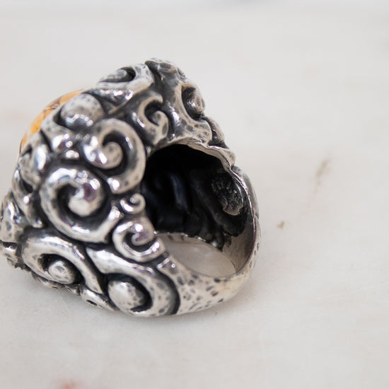 Silver ring with intricate designs on a marble surface
