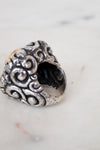 Silver ring with intricate designs on a marble surface