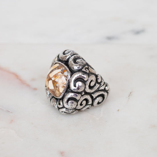Silver ring with a central mixed stone on a marble surface