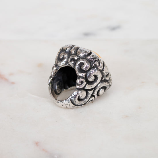 Silver ring with intricate design on a marble surface
