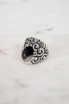 Silver ring with intricate design on a marble surface
