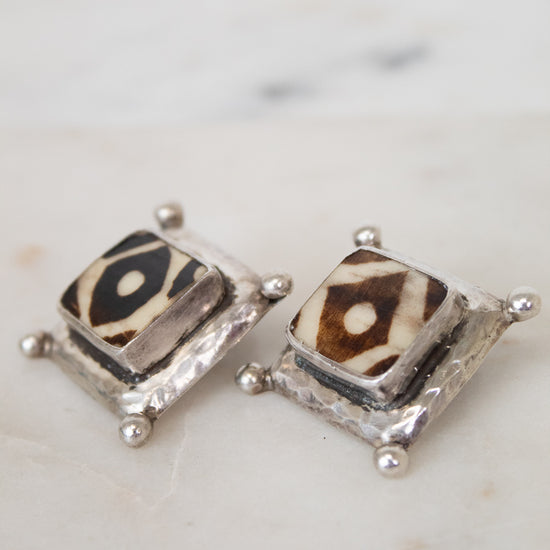 Pair of square-shaped earrings with animal print design on a marble surface