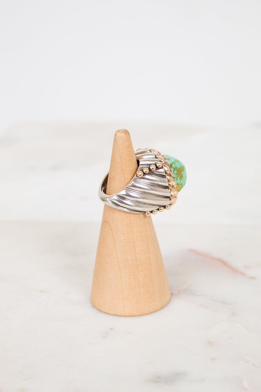 Ring with a turquoise stone on a wooden stand against a white background