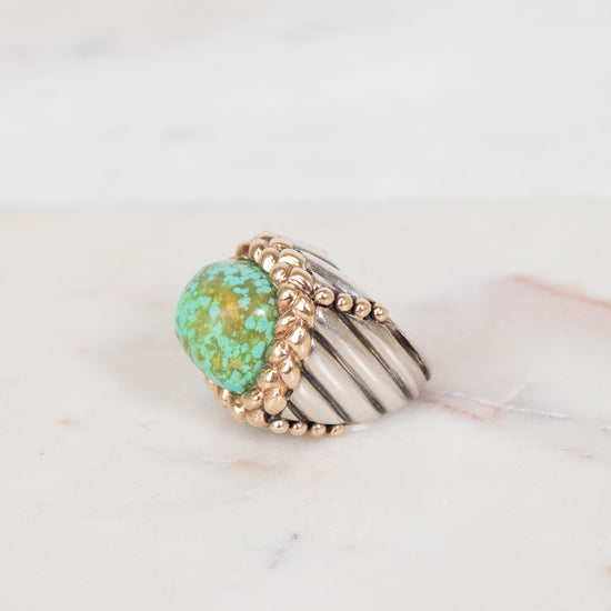 Gold ring with turquoise stone on a marble surface