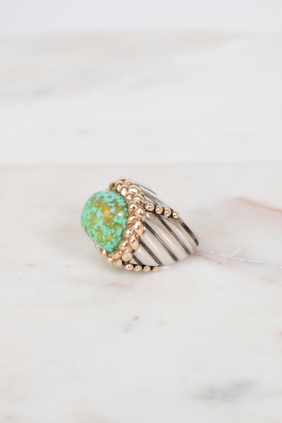 Gold ring with turquoise stone on a marble surface