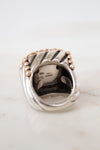 Silver ring with gold accents on a white marble surface