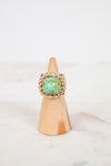 Ring with turquoise stone on a wooden cone against a white background