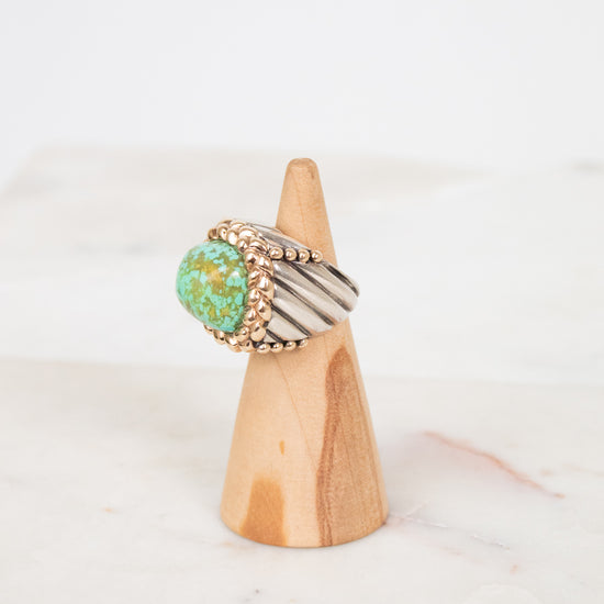 Two toned ring on a wooden cone with a white background