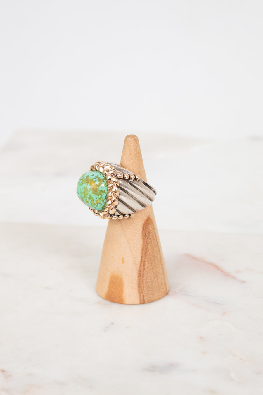 Two toned ring on a wooden cone with a white background