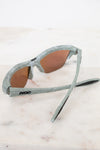 Sunglasses with gray and green frame on a light marble surface