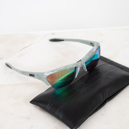 Sunglasses with reflective lenses on a black leather case against a white background