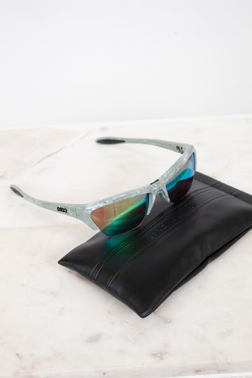 Sunglasses with reflective lenses on a black leather case against a white background