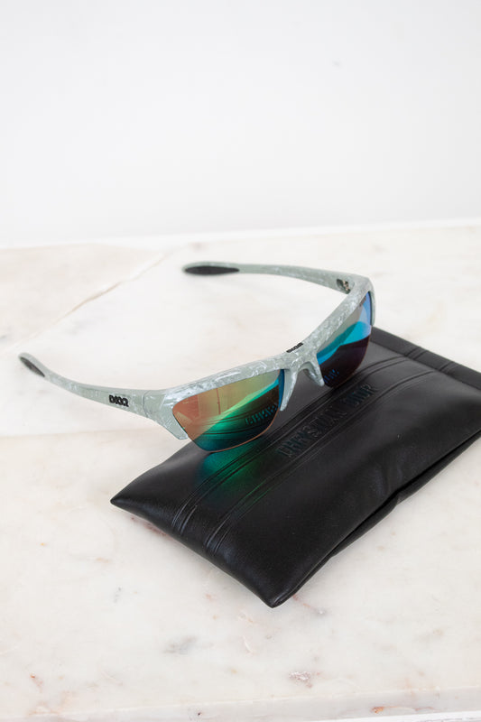 Sunglasses with reflective lenses on a black leather case against a white background