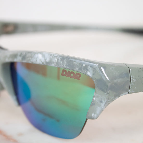 Close-up of a pair of sunglasses with 'Dior' branding on a blurred background