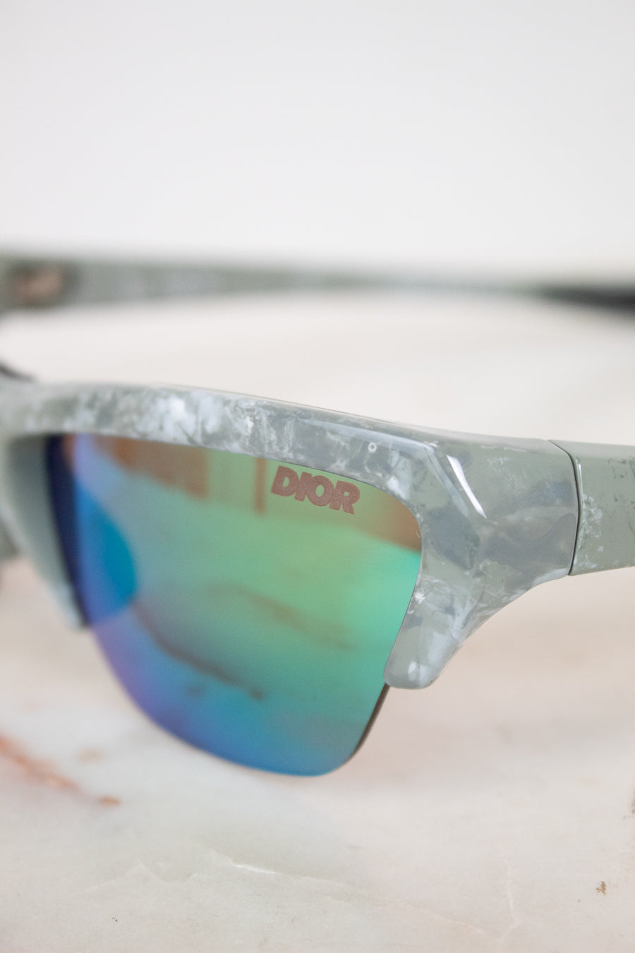 Close-up of a pair of sunglasses with 'Dior' branding on a blurred background