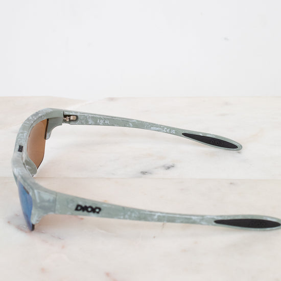 Sunglasses with a green and gray frame on a light marble background