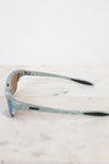 Sunglasses with a green and gray frame on a light marble background